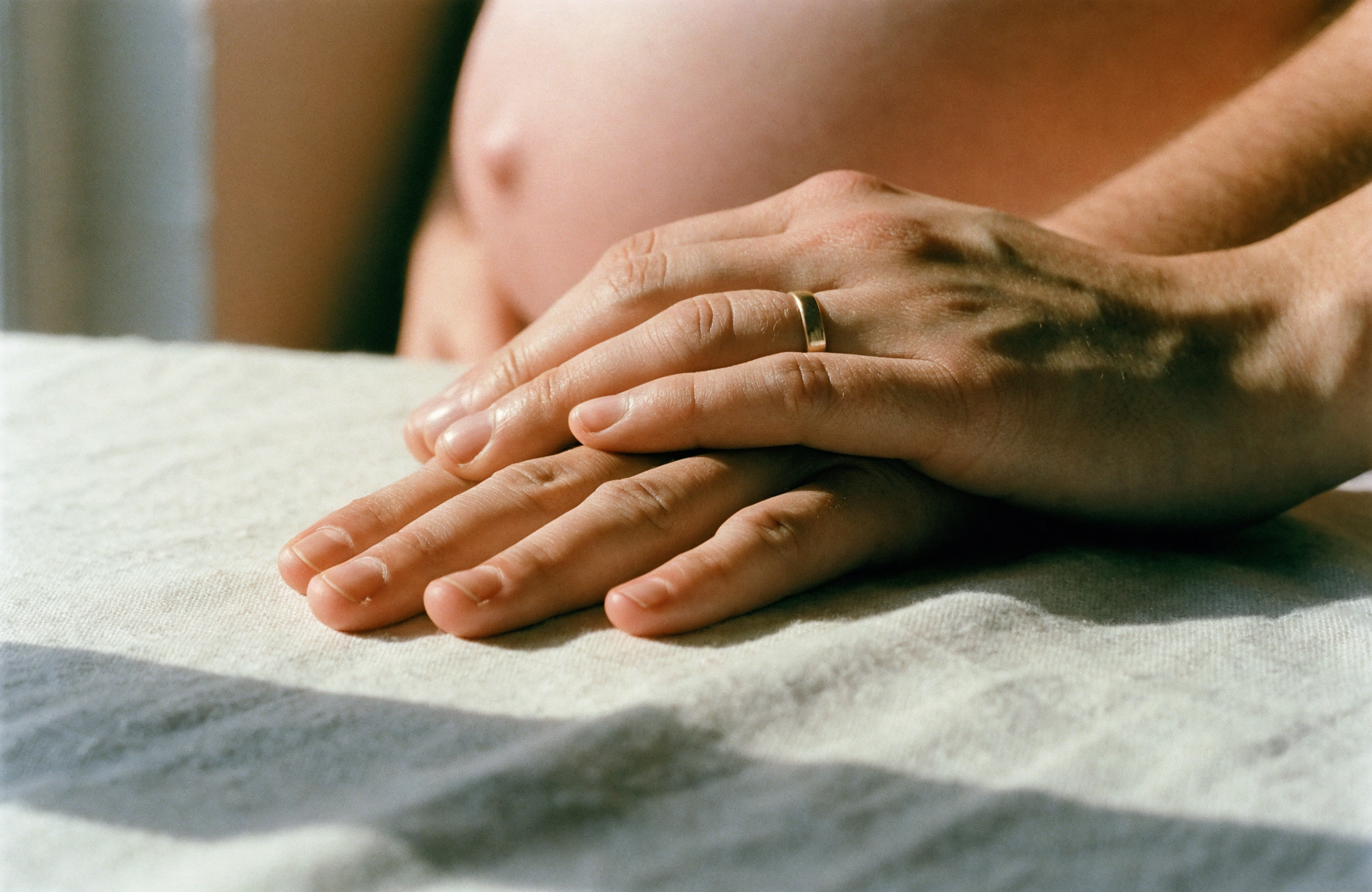 Two hands resting together on a linen tablecloth